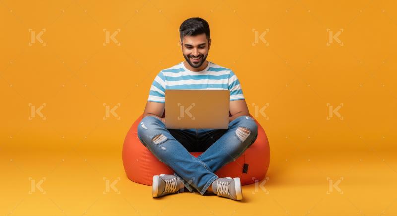 Happy Young Man Using Laptop on Orange Beanbag Chair