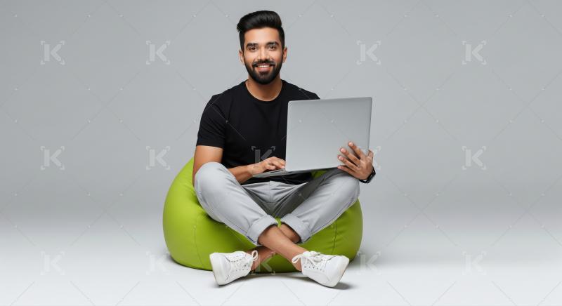 Smiling Young Man Working on Laptop on Green Bean Bag