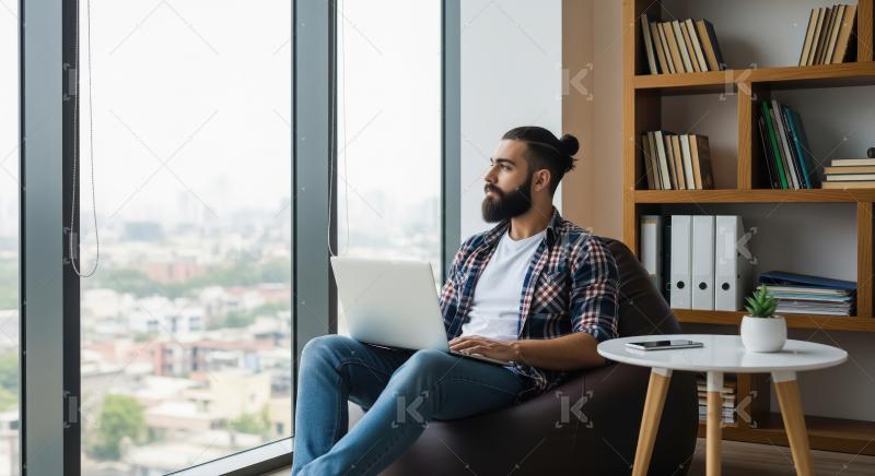 Young bearded man working comfortably on laptop overlooking city