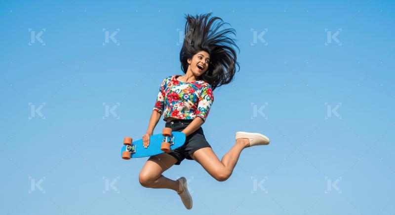 Joyful Young Indian Woman Jumps High with Skateboard