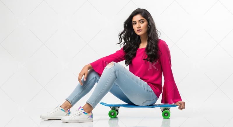 Young Indian woman sitting on a blue skateboard