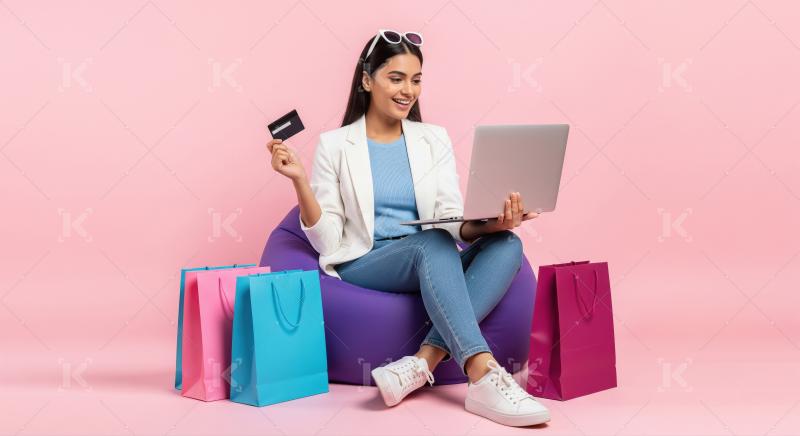 A young woman sits bean bag with a laptop and credit card, surro