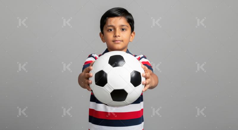 Adorable young boy holds soccer ball, ready for play.