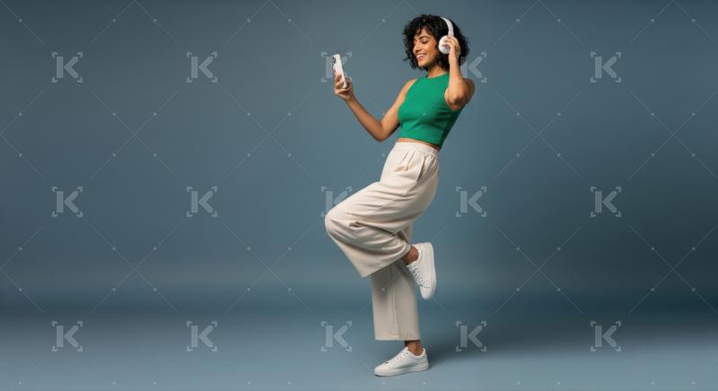 Young woman dancing happily while enjoying music from phone.