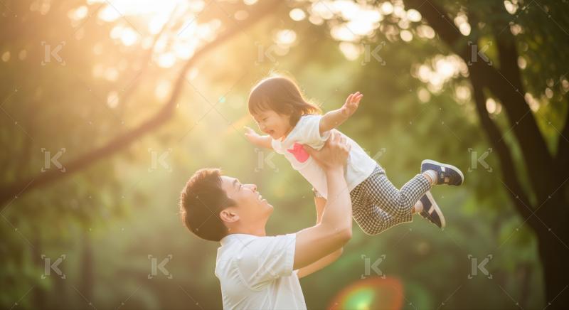 A joyful father lifts his daughter into the air outdoors, both smiling and enjoying a sunny moment together.