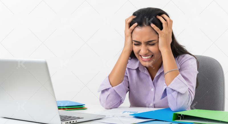 A young Indian woman in a lavender shirt sits at her desk with h