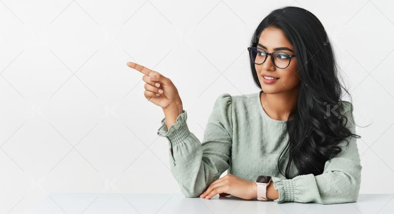 A stylish young Indian woman with long dark hair sits at a desk,
