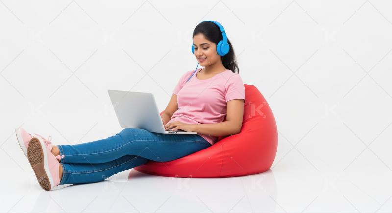 Young woman relaxing on bean bag with laptop and headphones