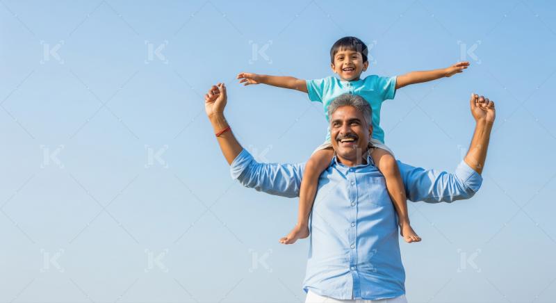 Happy Indian father and son bonding under vast blue sky