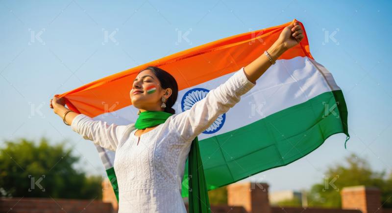 Young Indian woman proudly holds national flag under blue sky