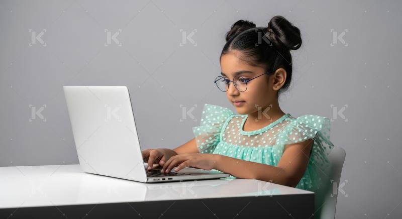Young Indian girl focused on learning with laptop.