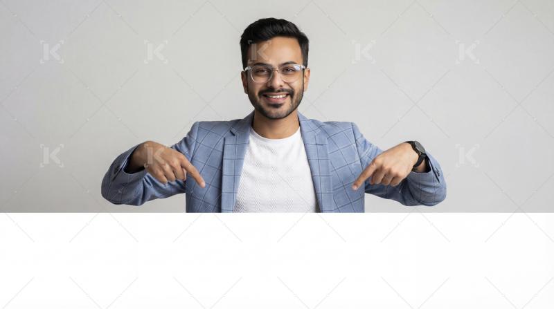 Smiling Young Man Pointing Down To Blank Copy Space