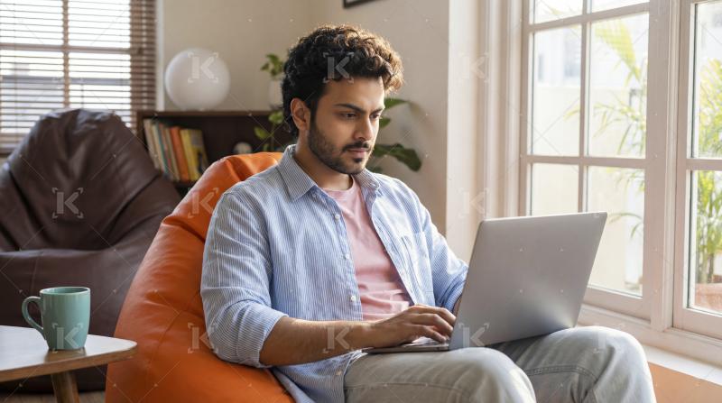 Indian man focused on laptop in cozy home setting